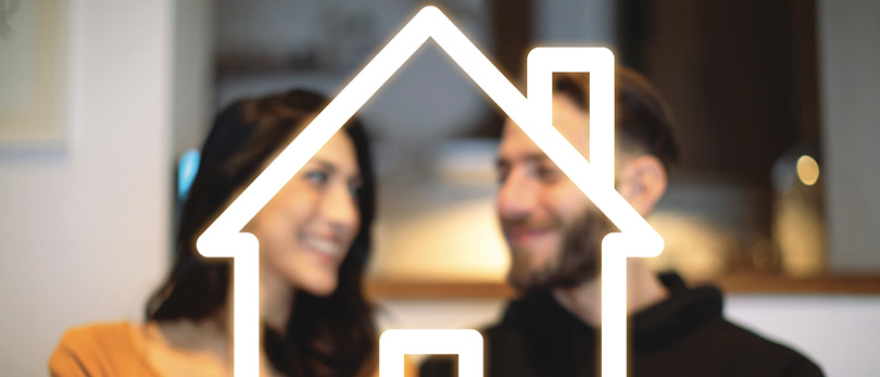 man and woman smiling behind home outline