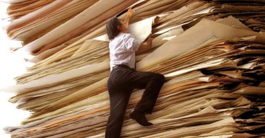 person climbing giant stack of paper