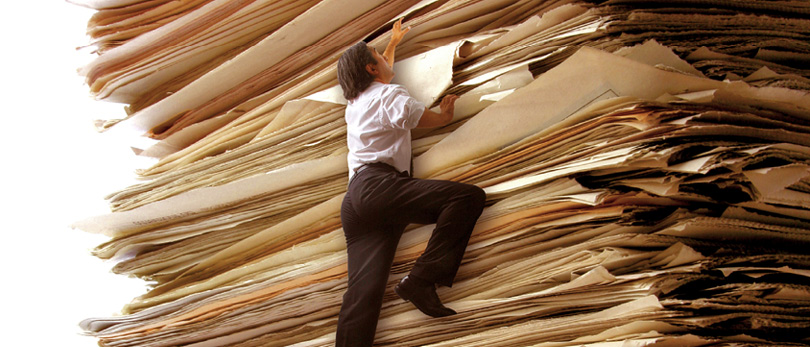 person climbing giant stack of paper
