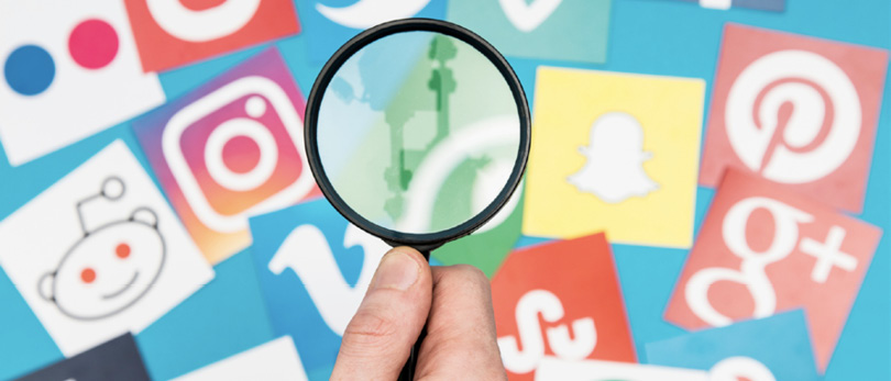 magnifying glass looking at social media icons