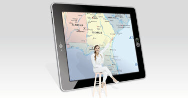 woman sitting in front of map on tablet