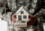 veteran holding a home with money underneath