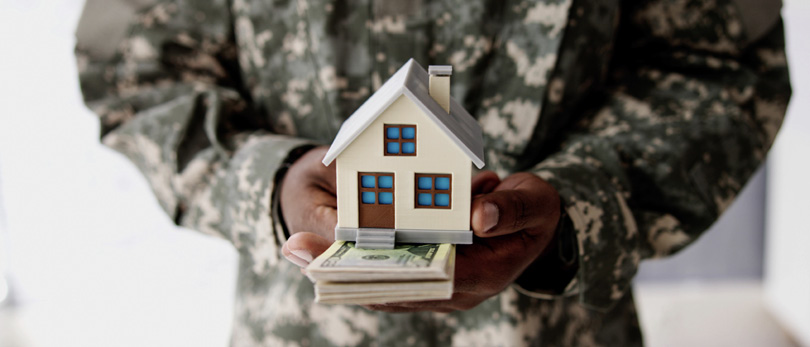 veteran holding a home with money underneath