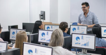 man teaching class involving computers