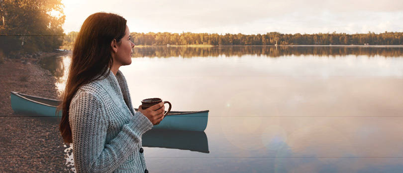 woman drinking coffee by lake