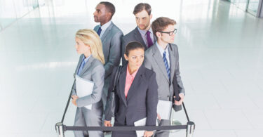 group of business professionals standing behind queue rope