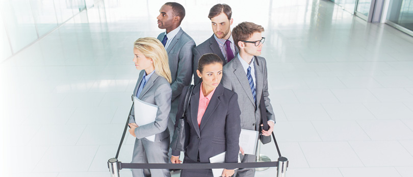 group of business professionals standing behind queue rope