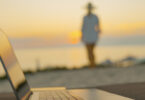 woman walking on beach with computer in foreground