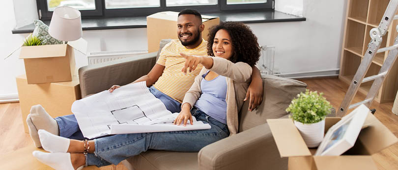 couple on couch looking at blueprints