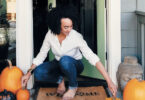 woman with fall decor on front stoop