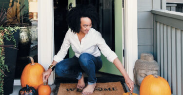 woman with fall decor on front stoop