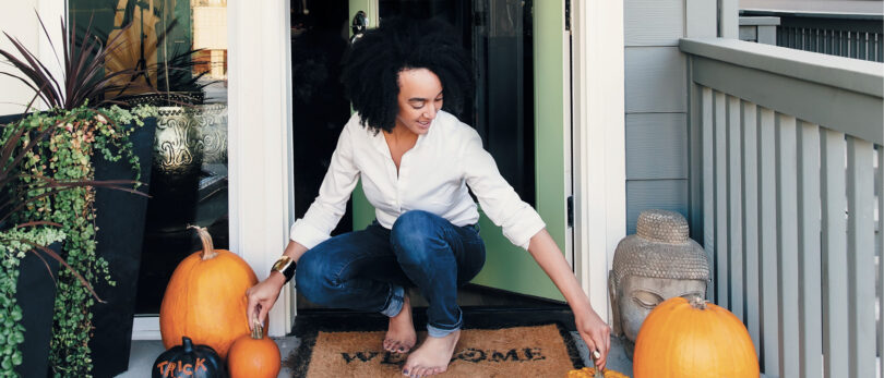 woman with fall decor on front stoop