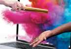 hands passing baton through computer with colorful dust