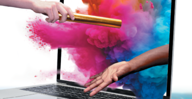 hands passing baton through computer with colorful dust